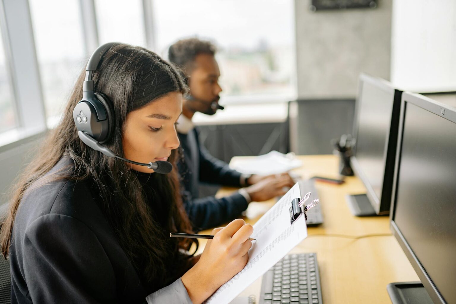 Customer service representative wearing headset at computer workstation
