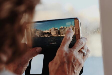 How YouTube’s Short-Form Algorithm Changes Affect Small Creators Person holding smartphone recording short-form video content for social media platform