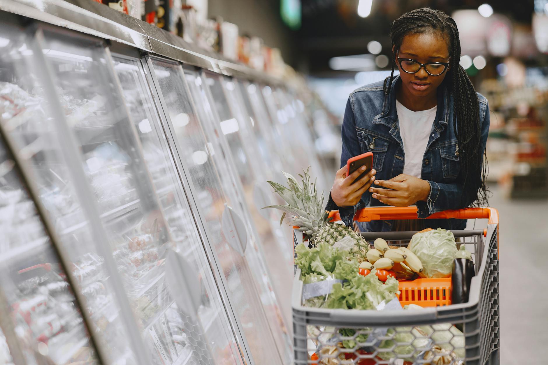 Person shopping for groceries in supermarket aisle with shopping cart