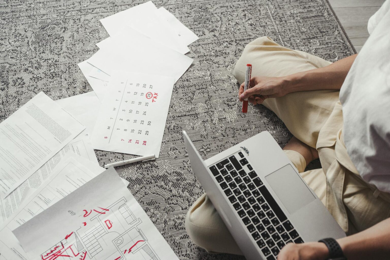 Person using laptop computer for wedding planning with documents and notes on desk