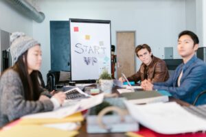 Diverse group of entrepreneurs collaborating around a conference table with laptops and notebooks