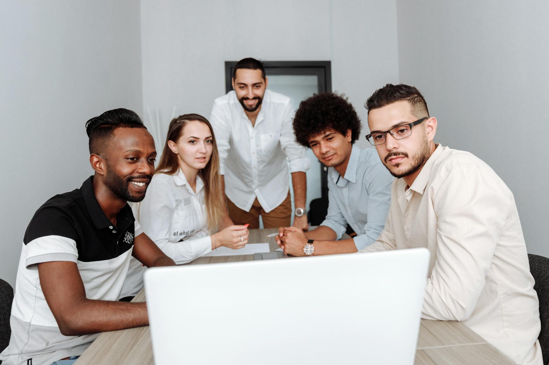 Creative team members collaborating around computer screens in modern office environment