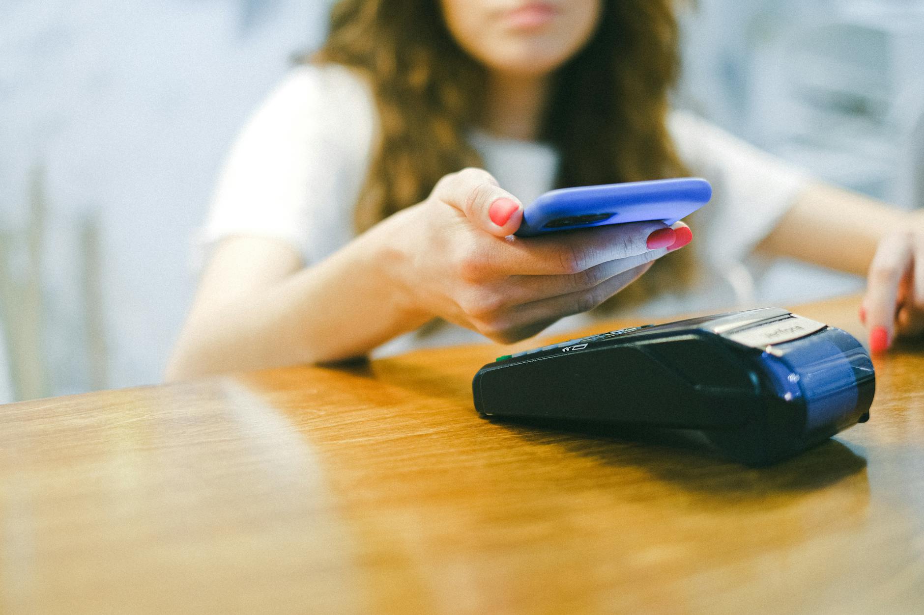 Person using smartphone to make mobile payment at counter