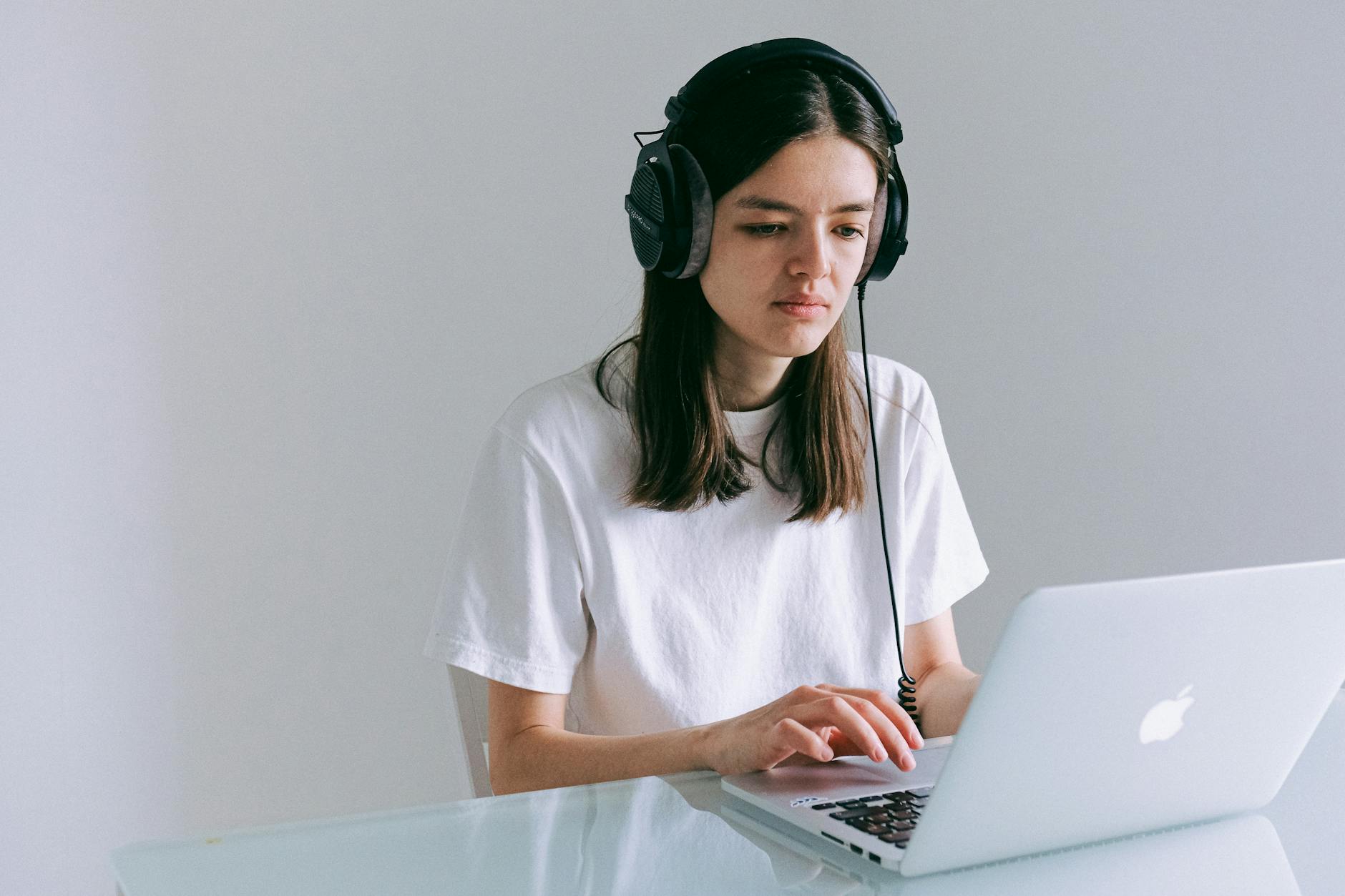Woman working on laptop while wearing headphones for audio content creation