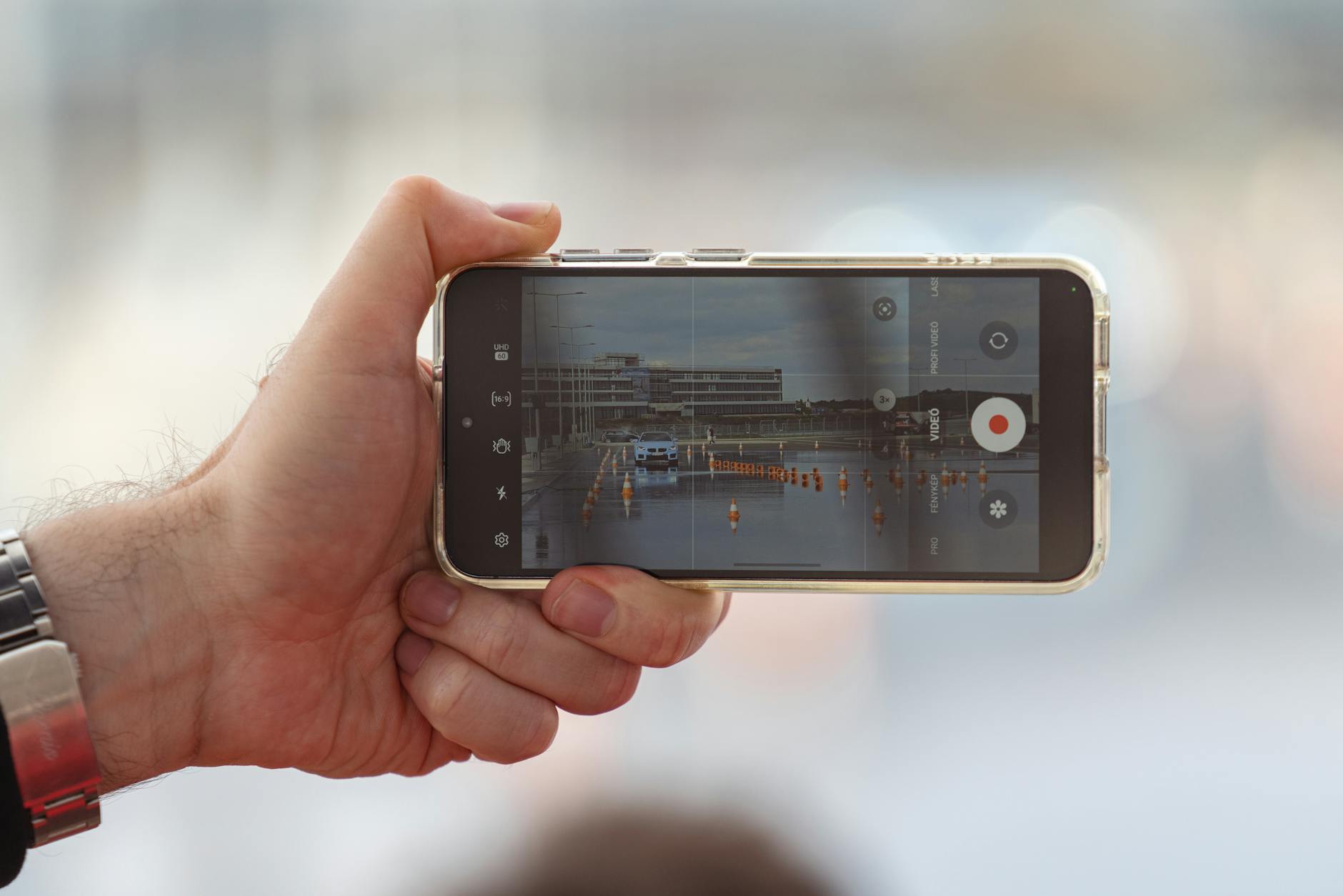 Hand holding smartphone in vertical position recording video content