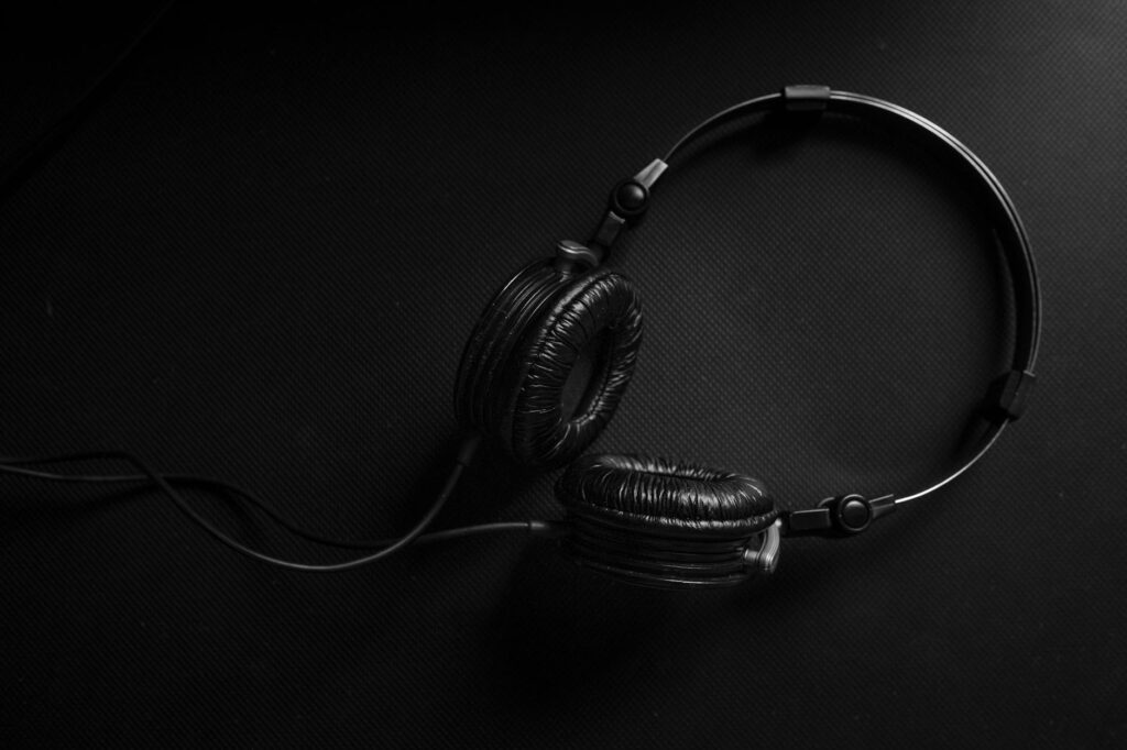 TikTok’s New Audio-Only Mode Is Attracting Podcast Listeners Smartphone with headphones in dark setting showing audio-only listening