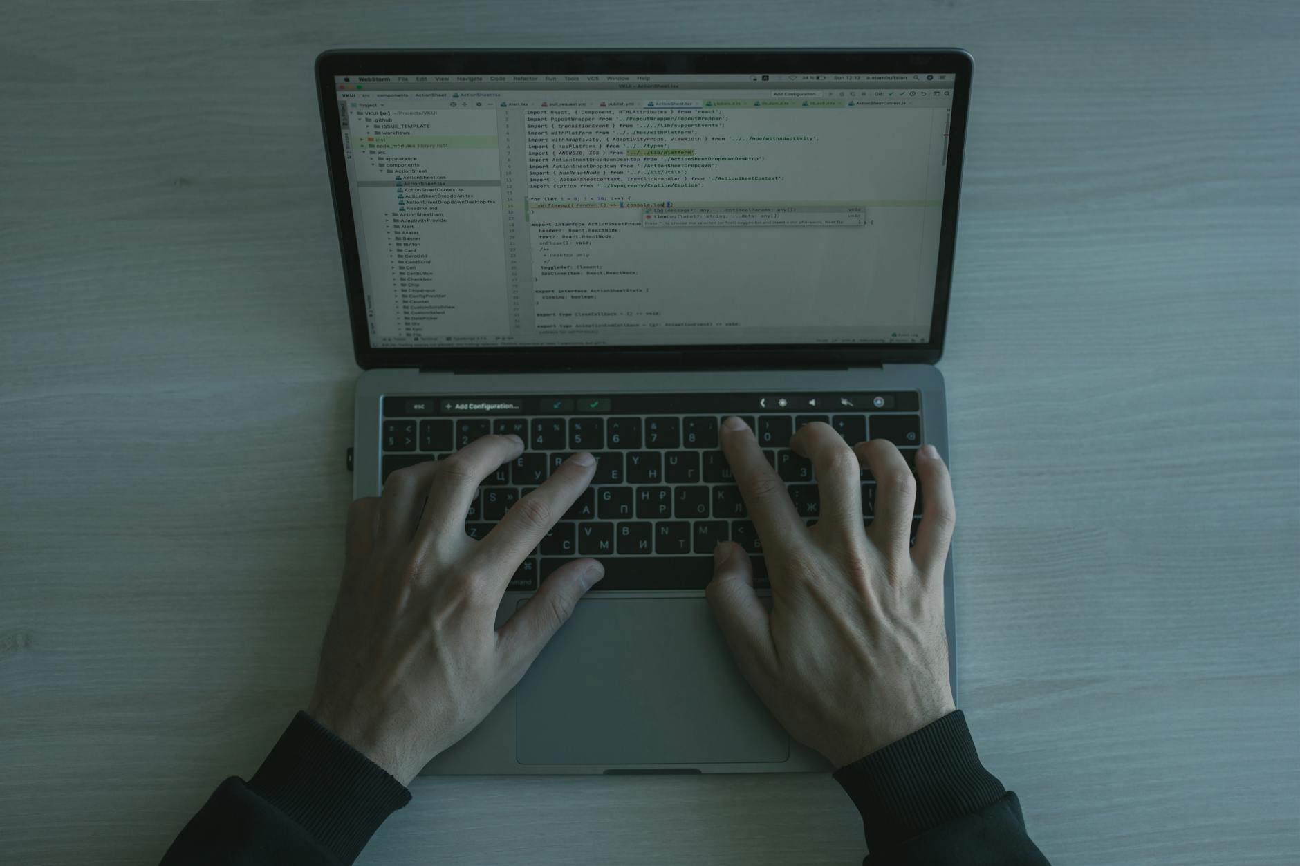 Hands typing on laptop keyboard with text on screen
