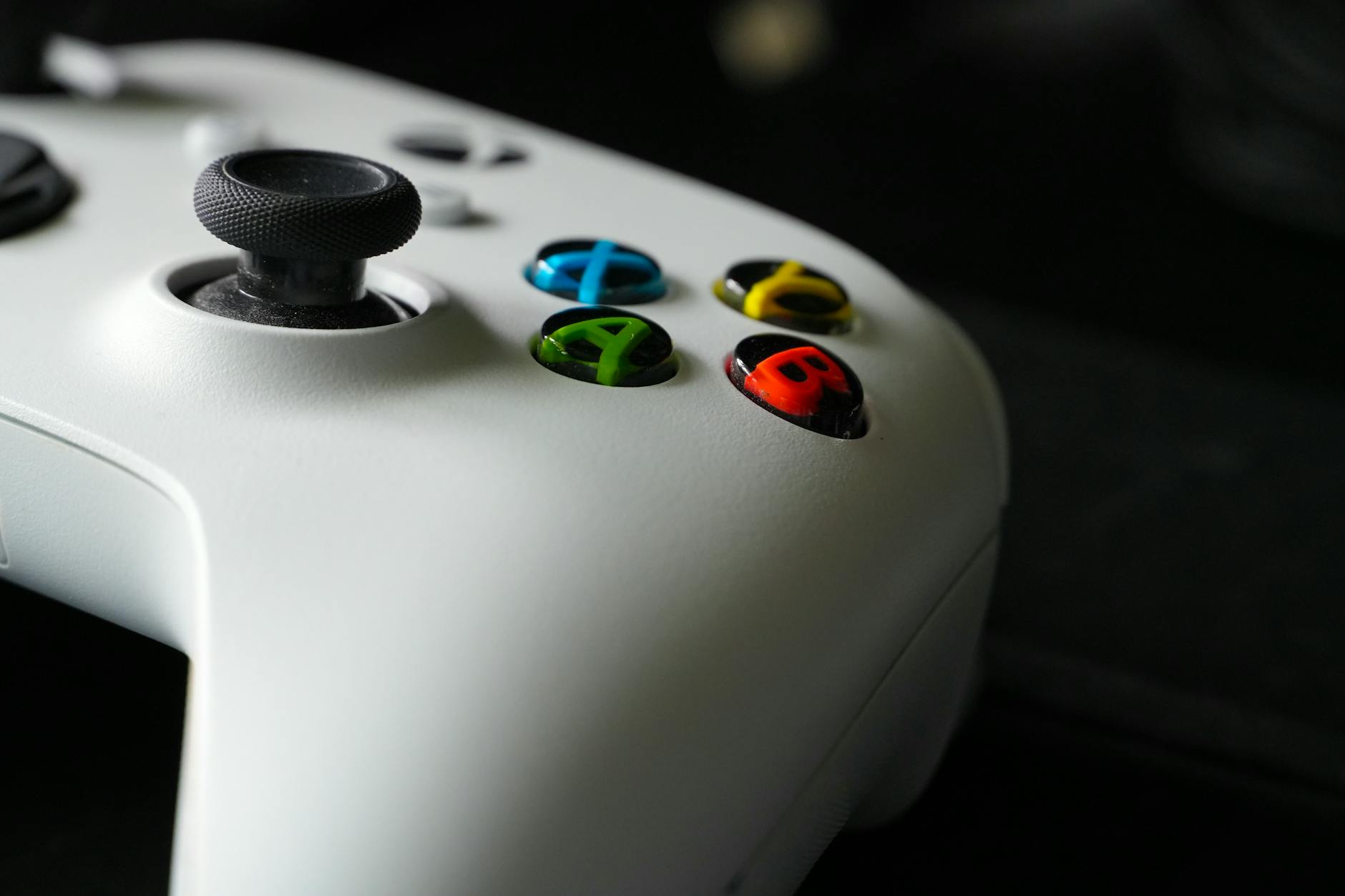 Gaming controller on desk next to keyboard and mouse in dimly lit gaming environment