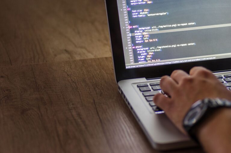 A developer working on backend code on a laptop at a modern desk setup