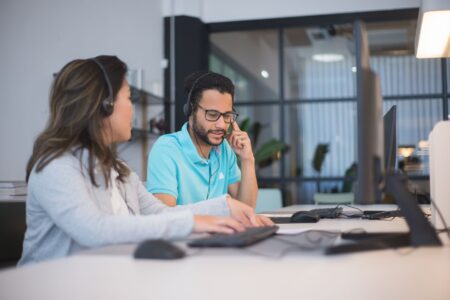 A customer support representative working at a computer in a modern office environment