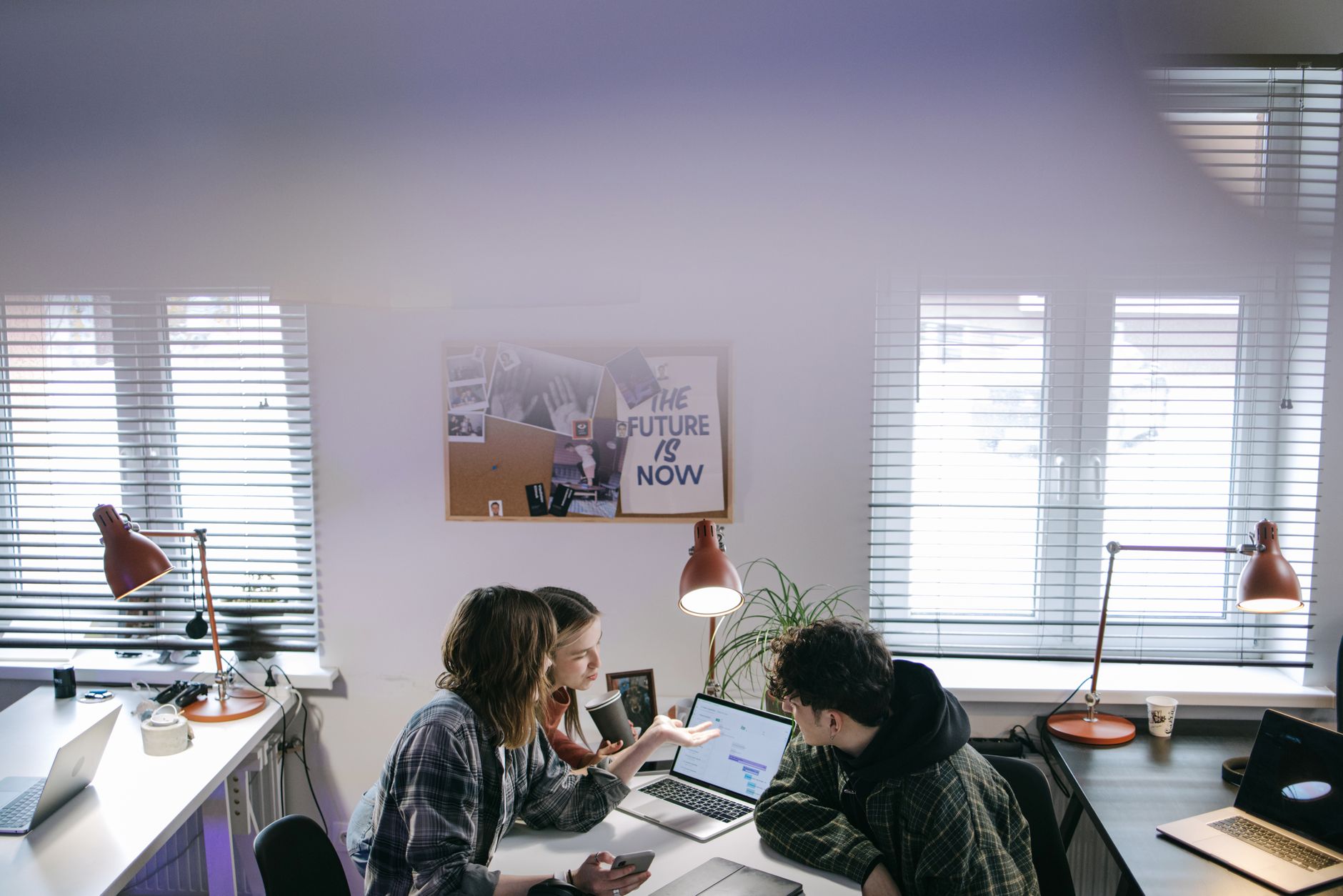 Two people collaborating on laptops in a modern office workspace