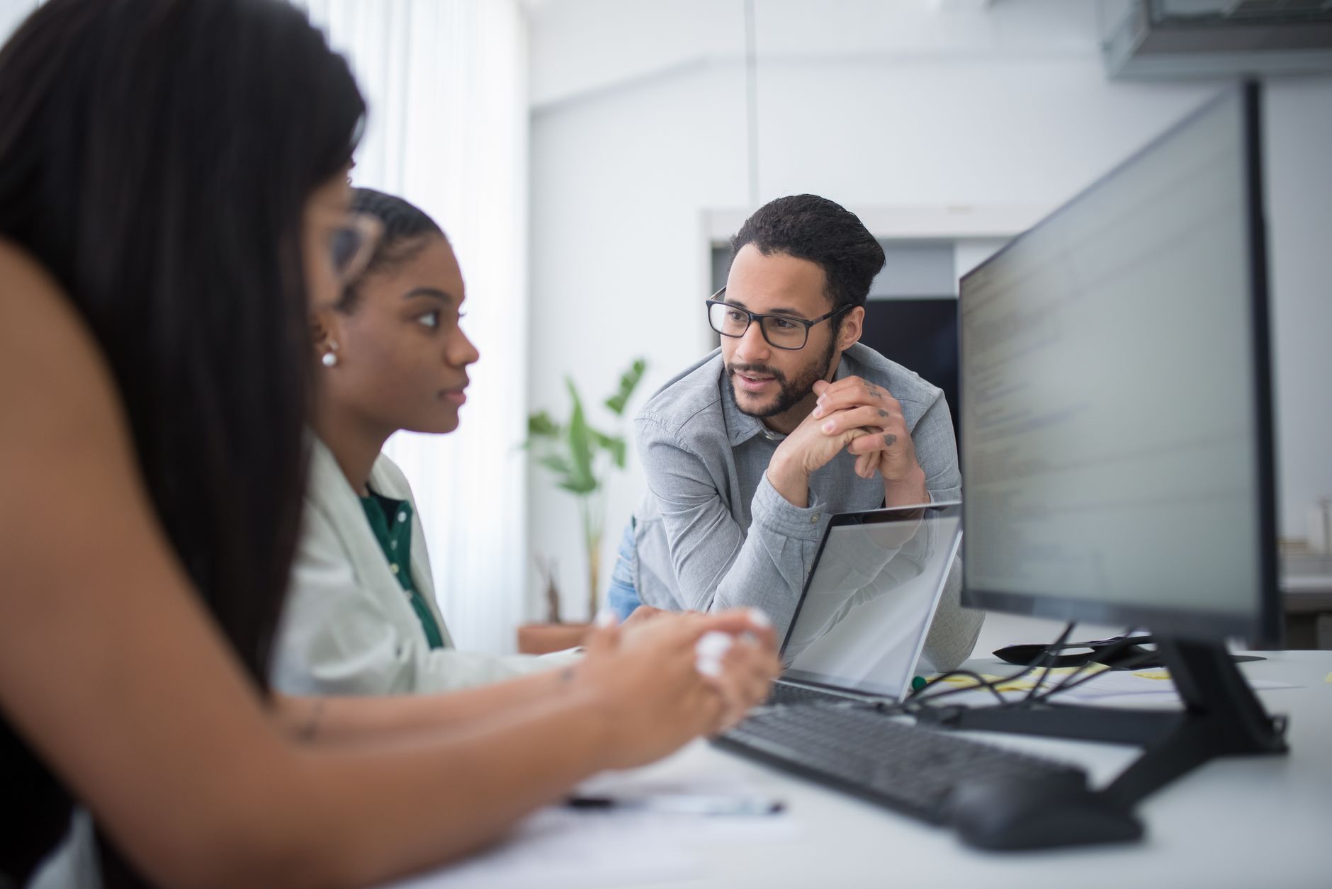 Two professionals reviewing software analytics on a laptop during a business meeting
