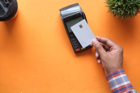 Person holding a credit card near a payment terminal