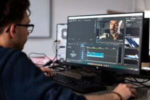 Descript’s Video Editing Push Is Crowding CapCut’s Creator Base A person editing video footage on a desktop computer with a timeline interface visible on screen