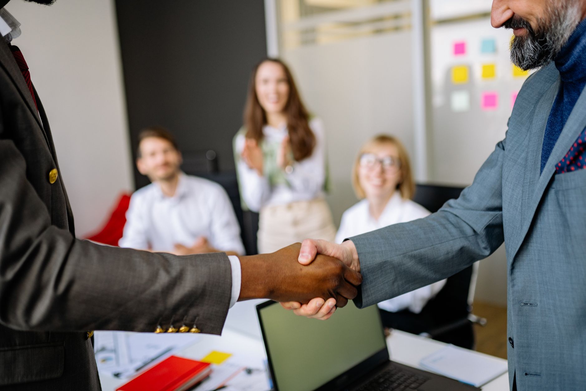 Two business professionals shaking hands over a signed agreement