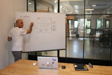A person working on a presentation at a modern desk with a laptop and monitor