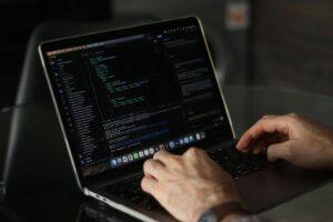 Developer writing code on a laptop screen in a modern workspace