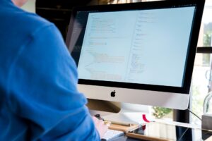 A developer writing code on a computer screen with multiple windows open