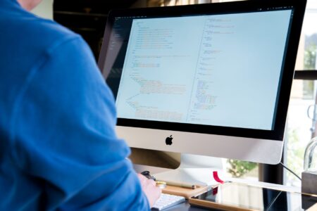 A developer writing code on a computer screen with multiple windows open