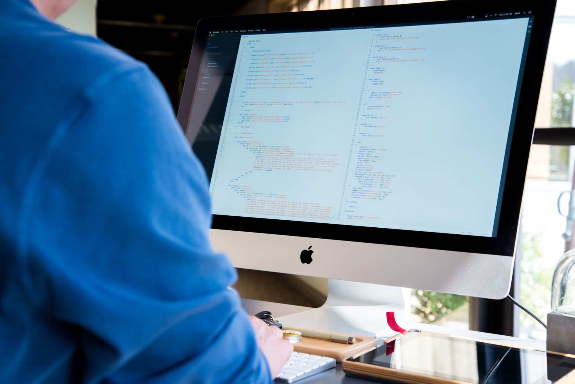 A developer writing code on a computer screen with multiple windows open