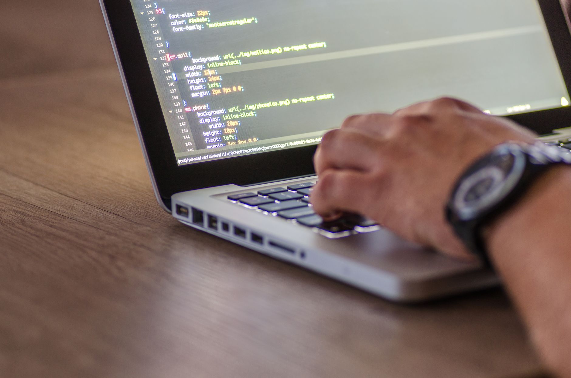 A developer working on a laptop with code on screen in a modern workspace