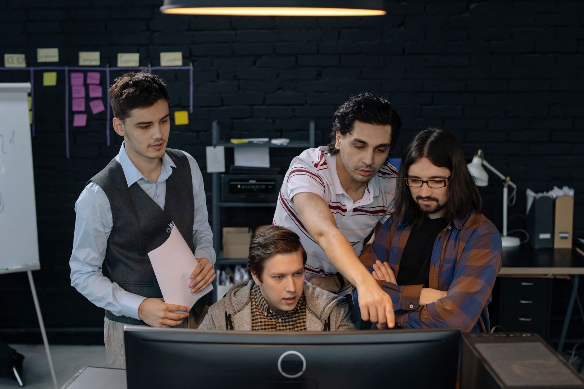 Engineering team collaborating around laptops in a workplace setting