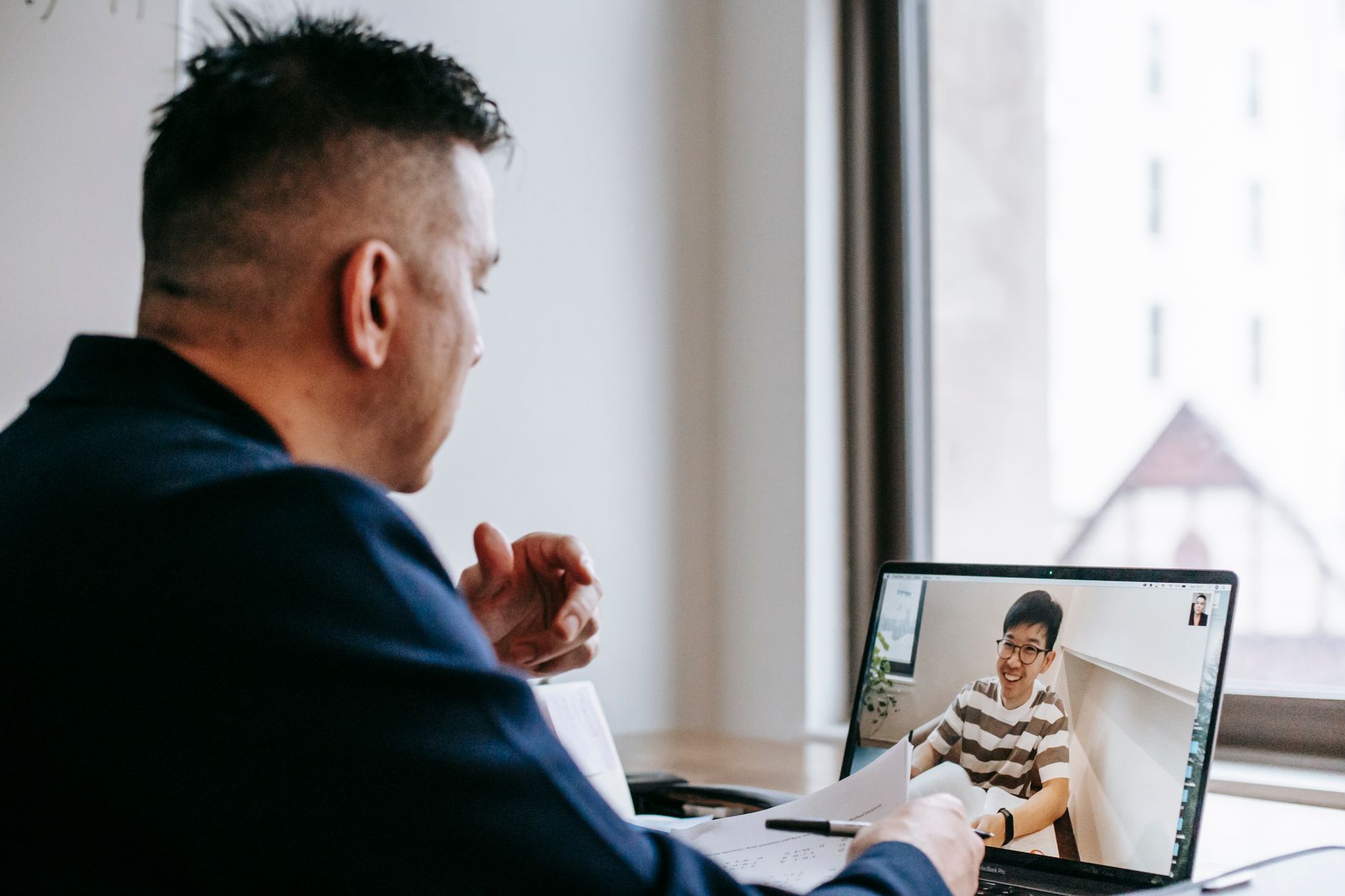 Person participating in a video conference call on a laptop in a modern office setting