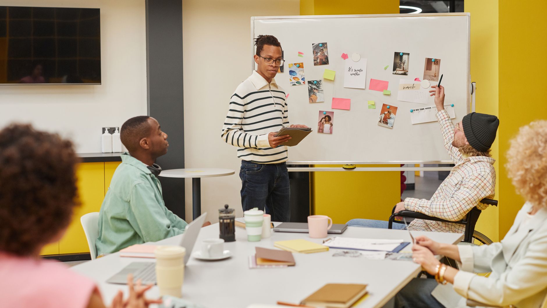 Product team collaborating around a table with laptops and design mockups