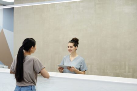 Hospital billing staff reviewing patient account statements at a front desk