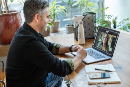 A professional participating in a video call meeting on a laptop
