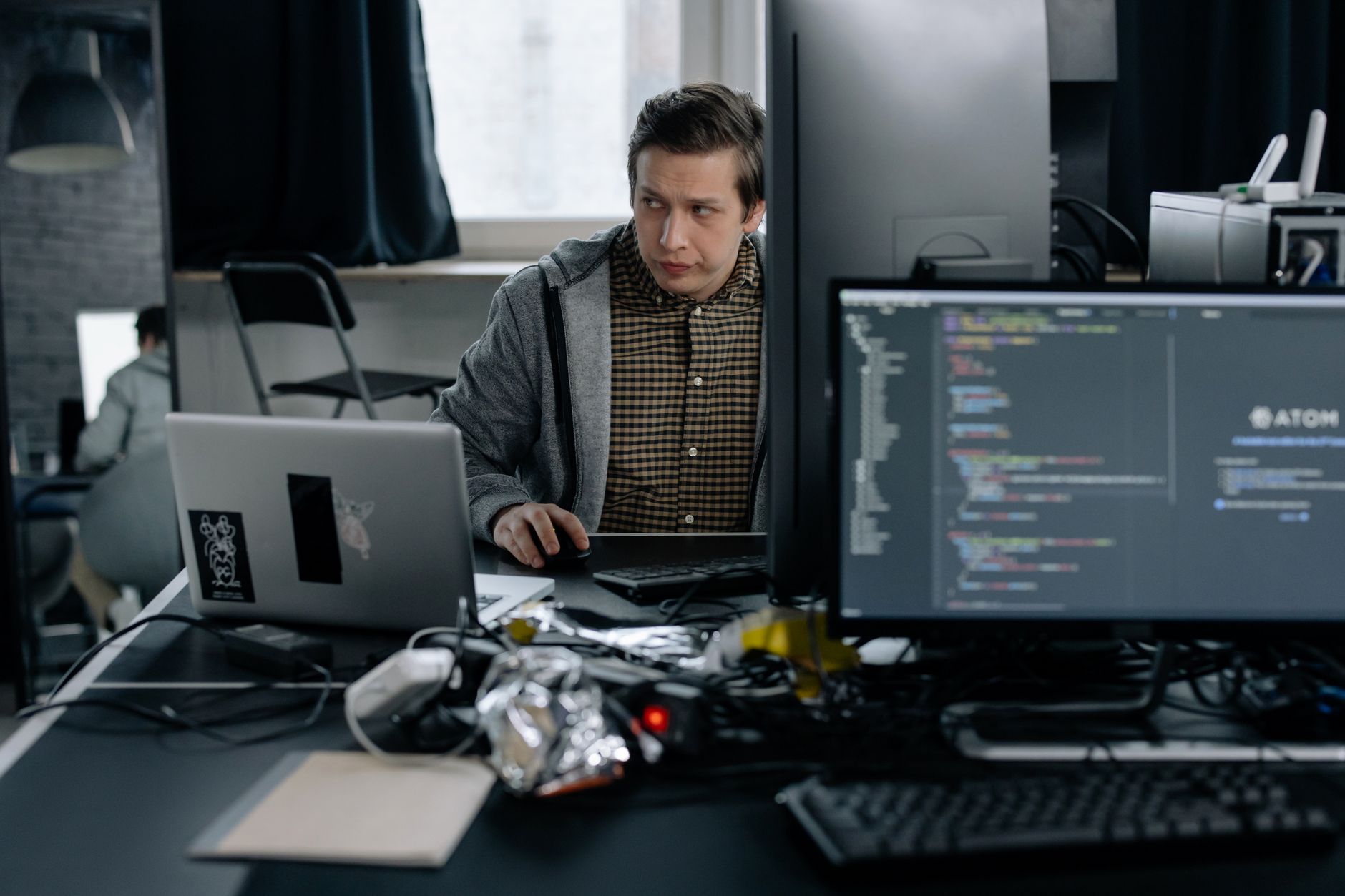 Software developer working at a desk with multiple monitors displaying code