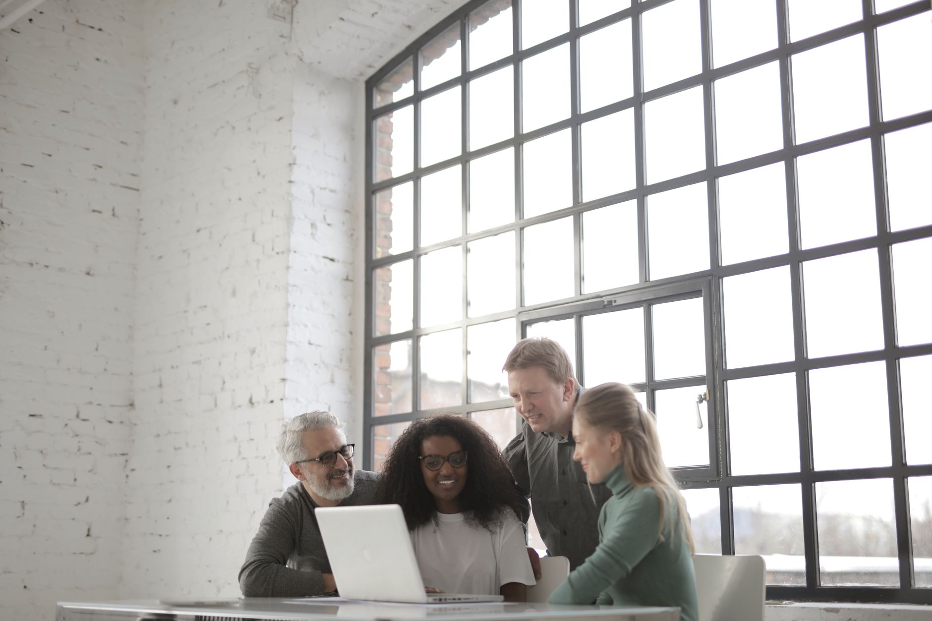 Knowledge workers collaborating around a shared digital workspace on laptops
