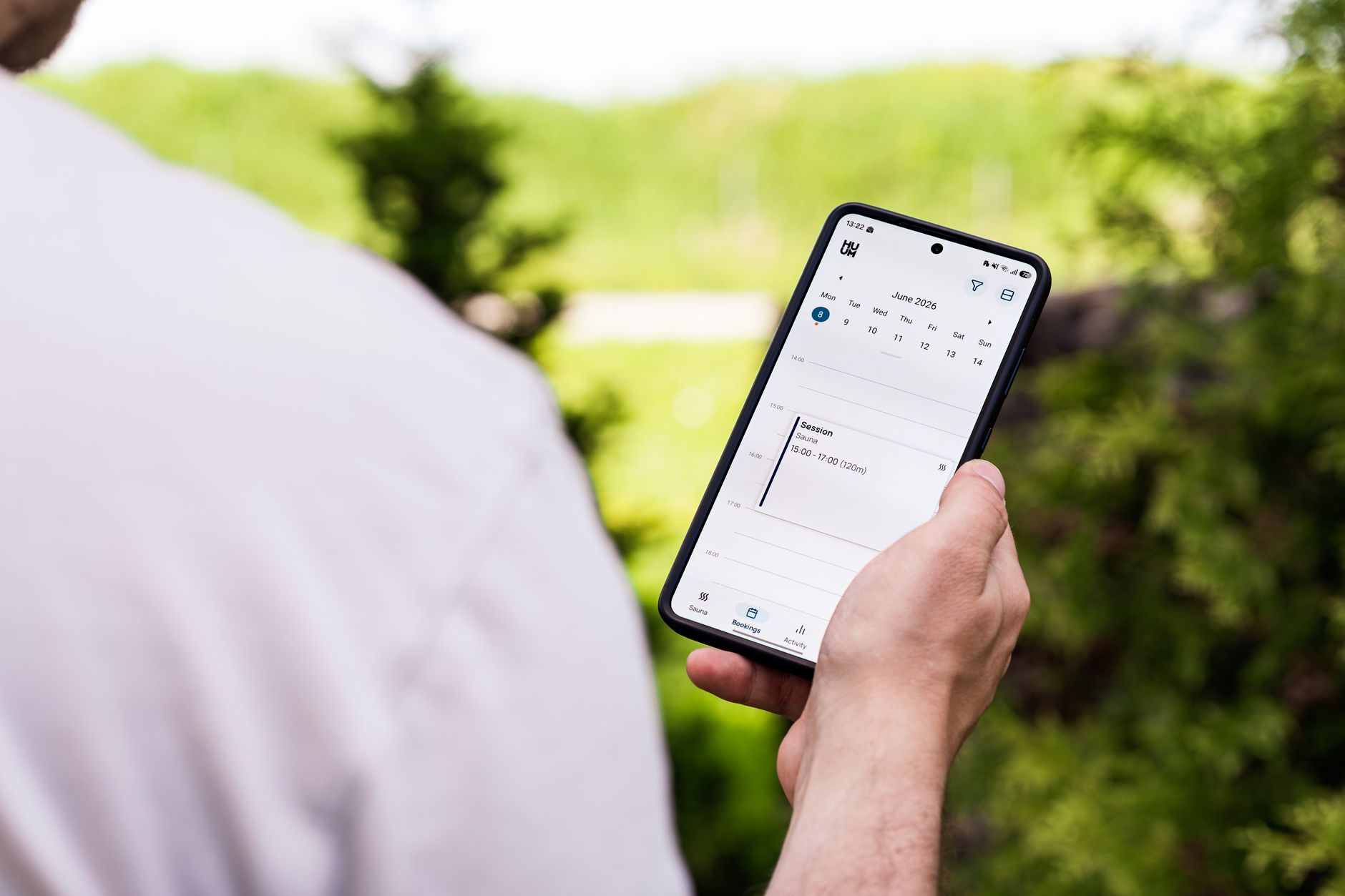 A person scrolling through a calendar app on a smartphone at a work desk